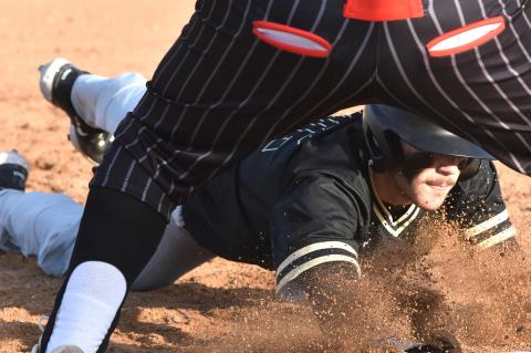 Coyt Bell dives back to first to avoid the tag in the season opener Saturday 